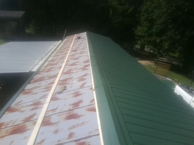 Old rusted panels beside newly installed green metal roofing — Wind Damage Roof Repair by Roofing Brothers in Lexington